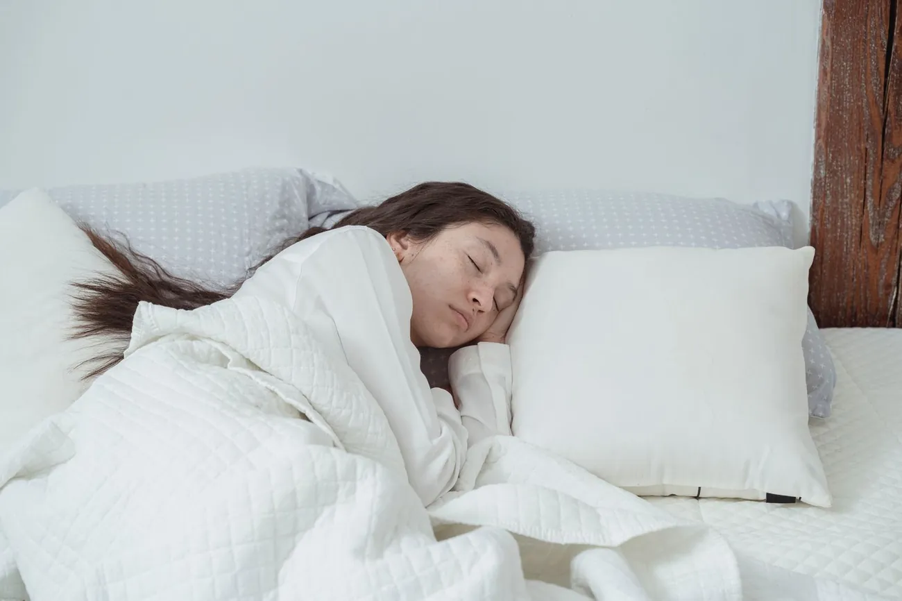 How to sleep better naturally: woman sleeping peacefully in a bright, calm bedroom